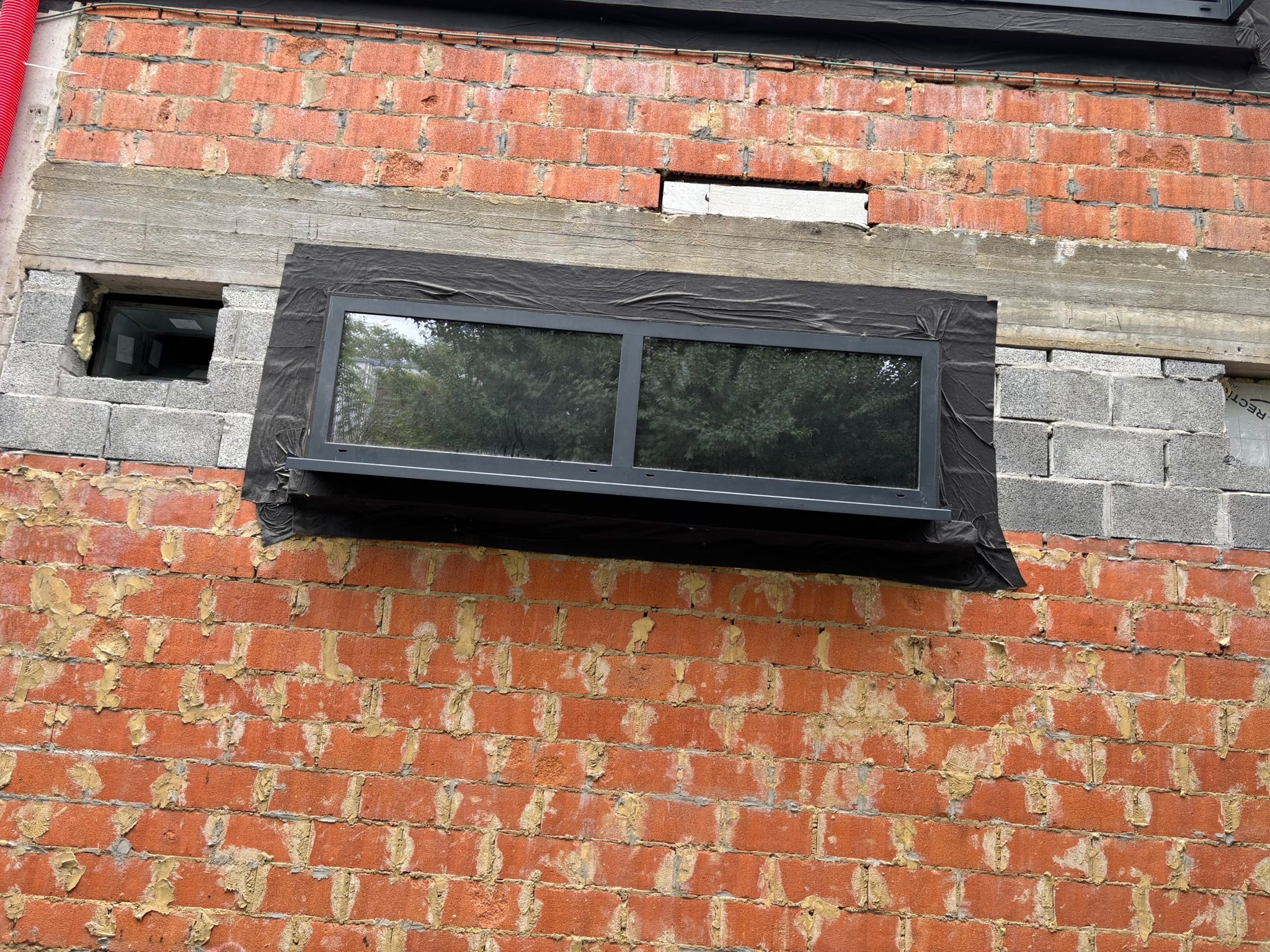 Fenêtre en saillie à cadre anthracite dans un mur de briques