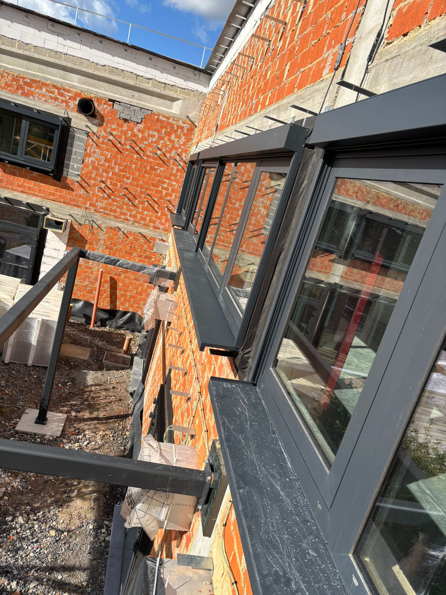 Bandes vitrées en saillie posées depuis l’échafaudage sur une façade en rénovation