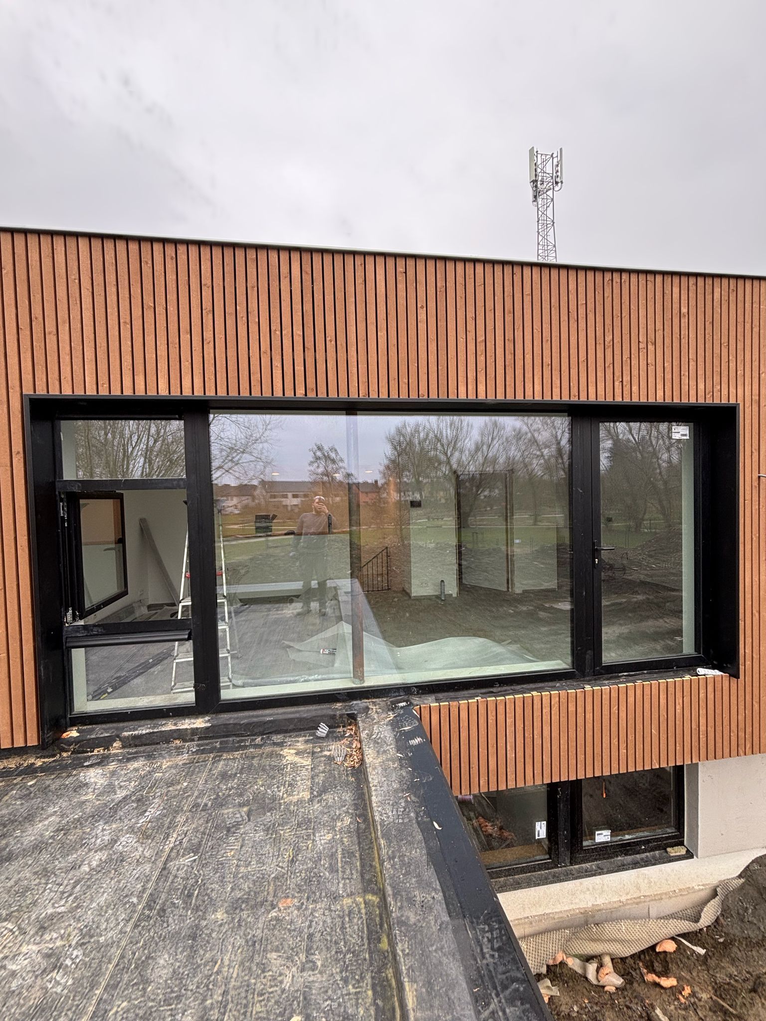Façade en bardage bois et large châssis anthracite, vue depuis la toiture plate
