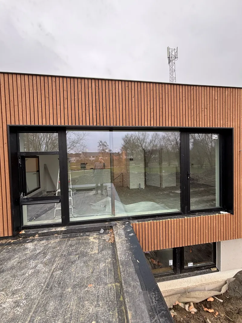 Façade en bardage bois et large châssis anthracite, vue depuis la toiture plate
