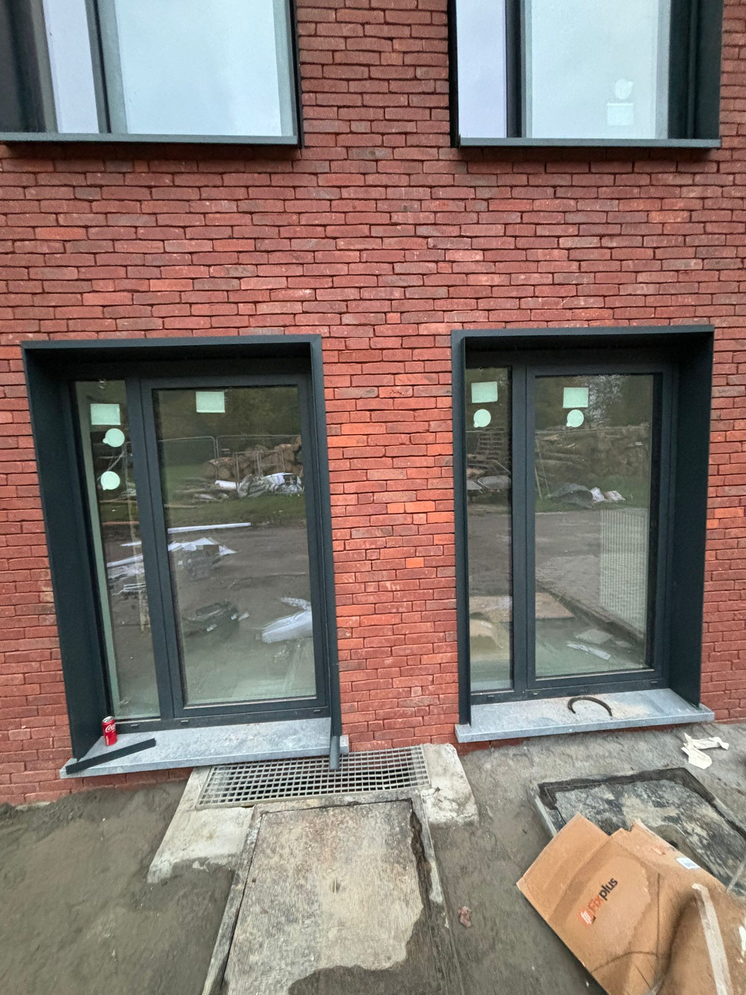 Deux portes-fenêtres anthracite au rez-de-chaussée d’un bâtiment en briques