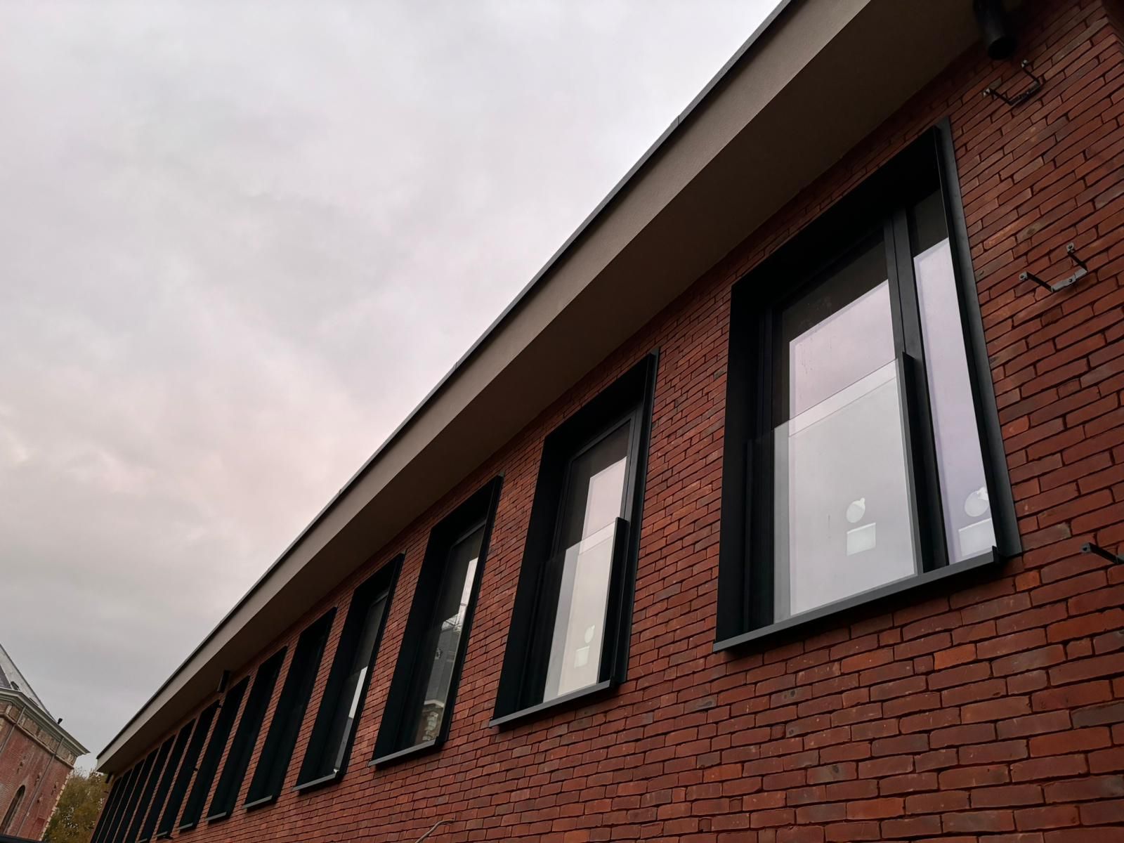 Façade en briques en perspective avec ses fenêtres anthracite alignées
