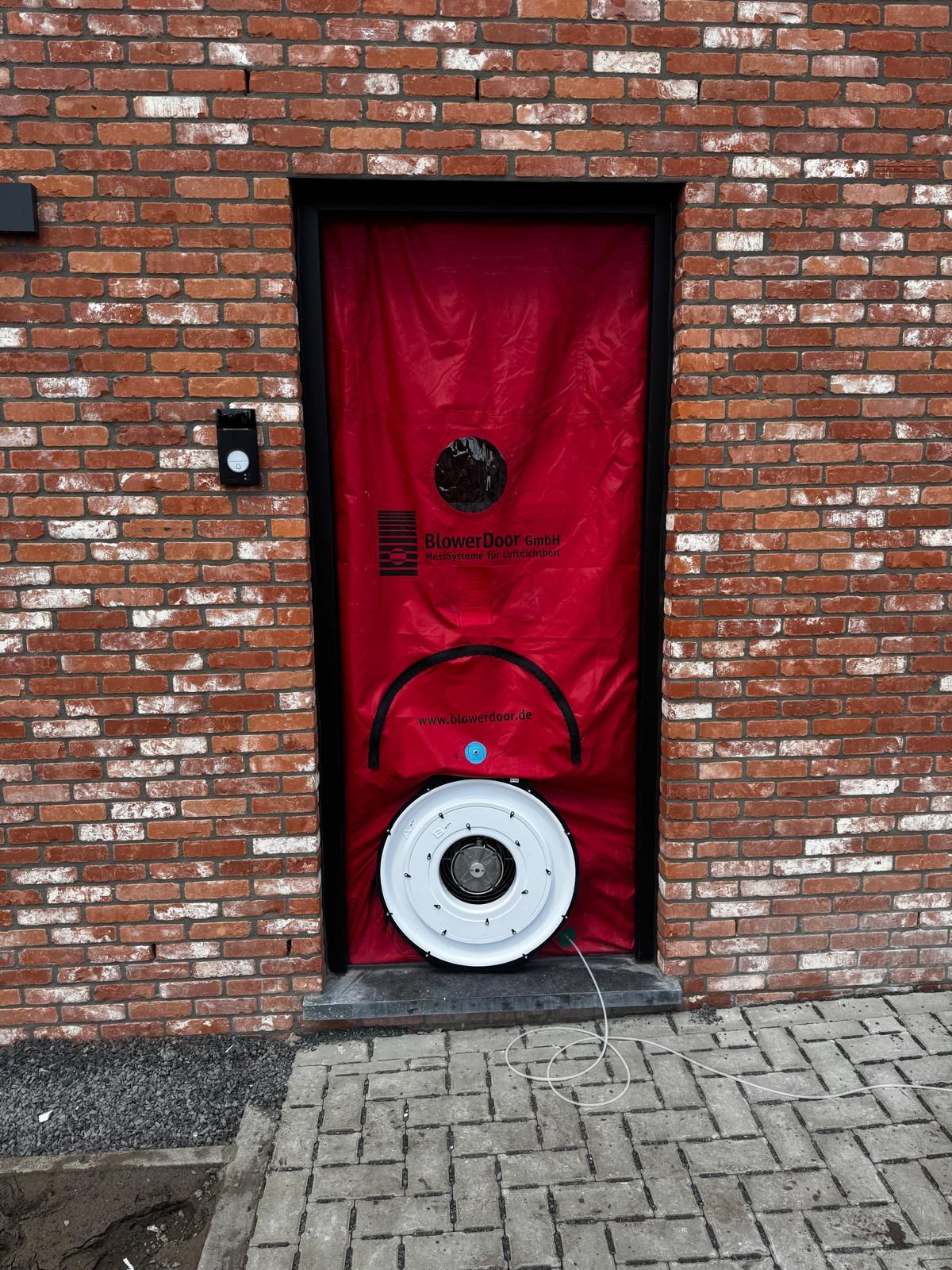 Test d’étanchéité à l’air : porte soufflante dans une façade en briques rouges