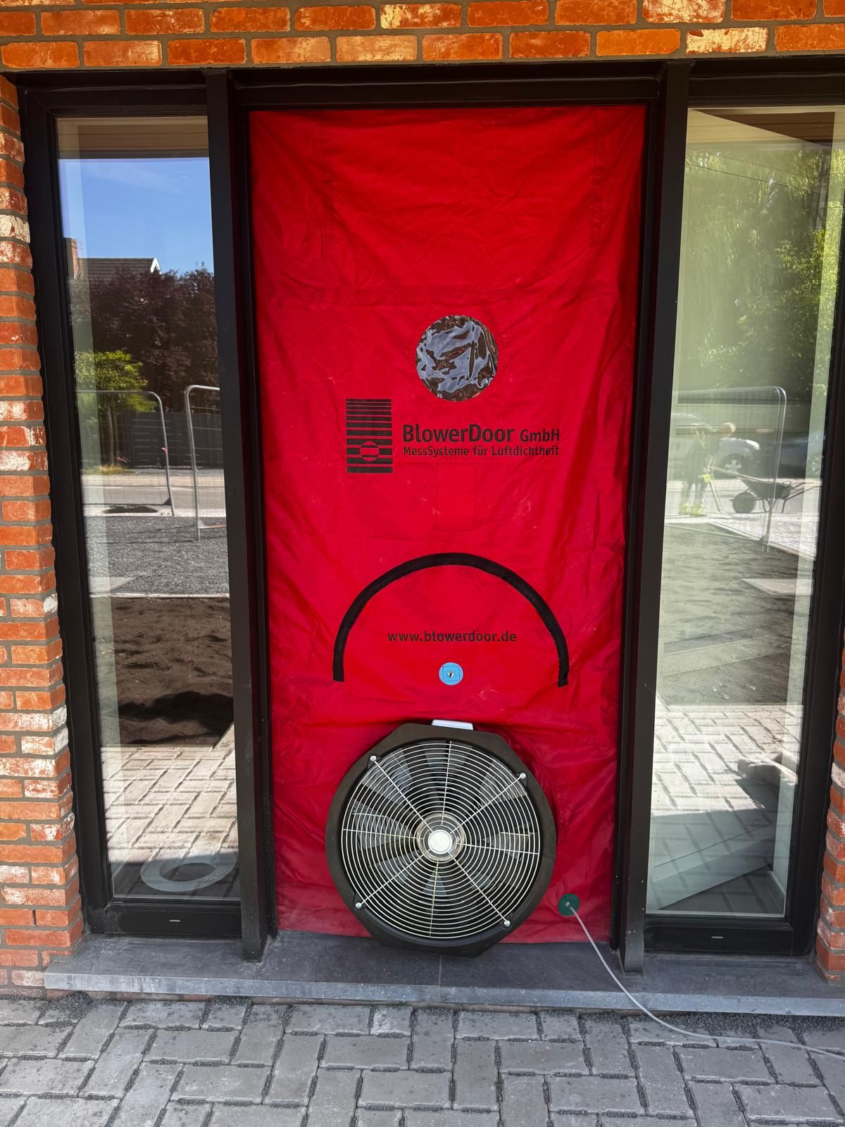 Porte soufflante installée dans une entrée vitrée, ventilateur en bas de la toile